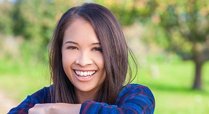 Woman in flannel smiling after teeth whitening