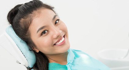 Woman sitting back in dental chair smiling