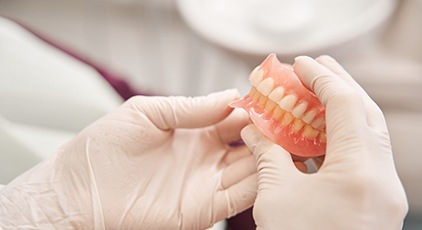 Gloved hands holding complete set of dentures