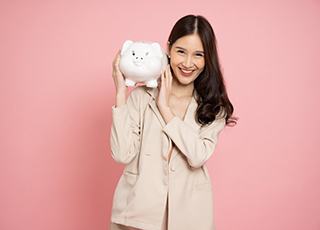 Woman holding a piggy bank and smiling on pink background